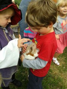 2 boys holding a white and brown guinea pig